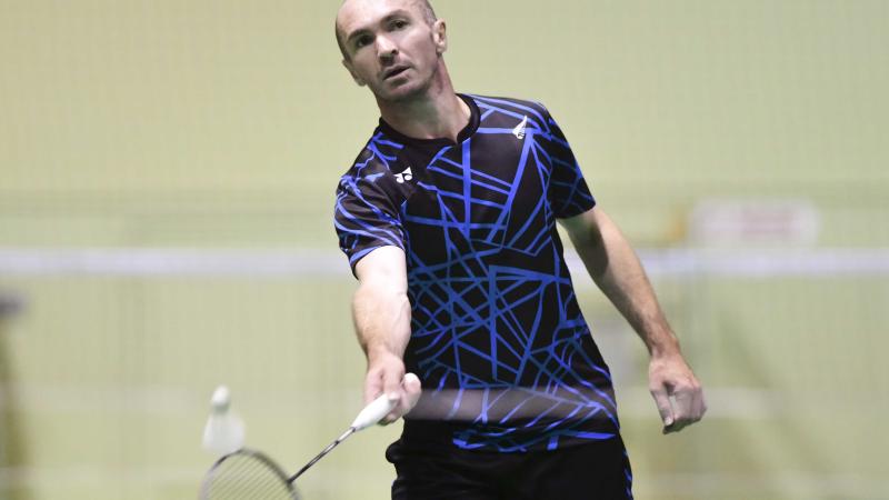 male Para badminton player Corrie Keith Robinson standing and playing a forehand shot