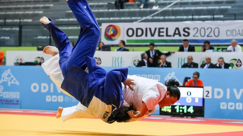 Judokas holding each other while falling onto the tatami