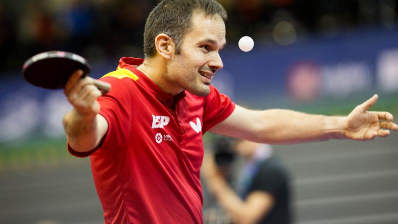 male Para table tennis player Jordi Morales raises his arms at the table 