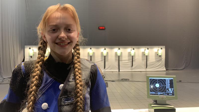 female Para shooter Iryna Shchetnik smiling in front of a row of targets