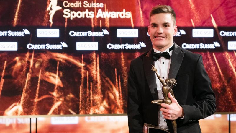 Swiss male in a suit holding an award