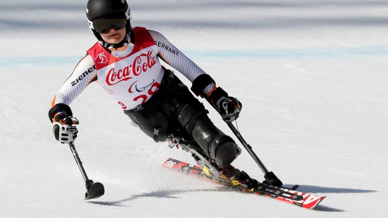 female Para alpine skier Anna-Lena Forster leans to the left as she skis down the slope