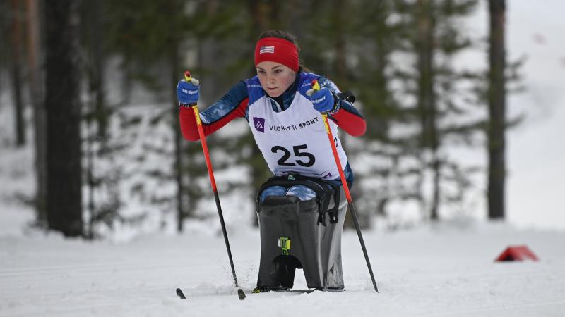 female Para Nordic sit skier Kendall Gretsch pushing through the snow