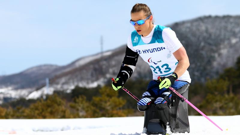 female sit skier Oksana Masters pushing through the snow