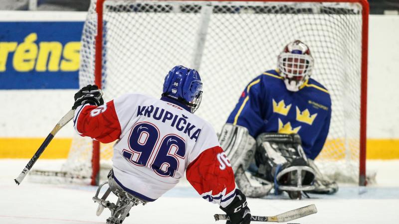 A Para ice hockey player taking a shot in front of the opponent's goal