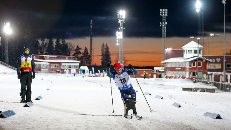 A man in a sitting ski competing in a biathlon race