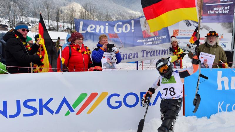 A sit-skier celebreating in front of a group of five people