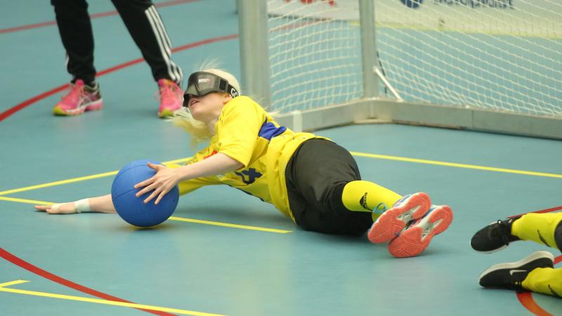 a female goalball player makes a save on the ground