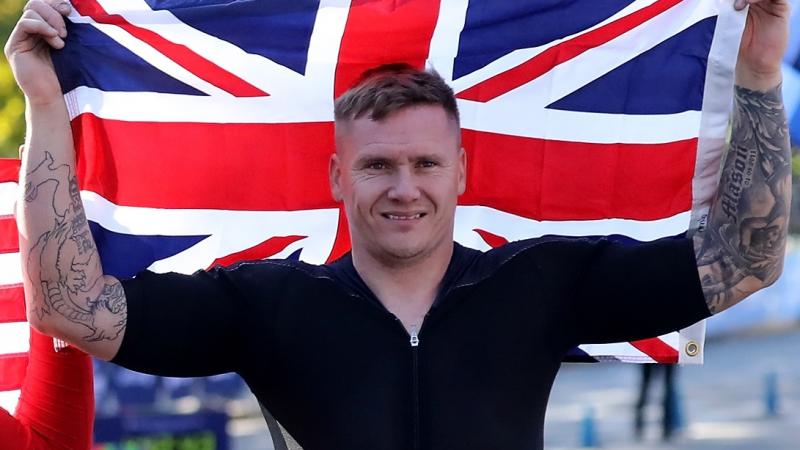 male marathon wheelchair racer David Weir holding up the British flag and smiling