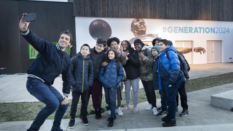 Tony Estanguet takes a selfie with some schoolchildren outside a school in Paris