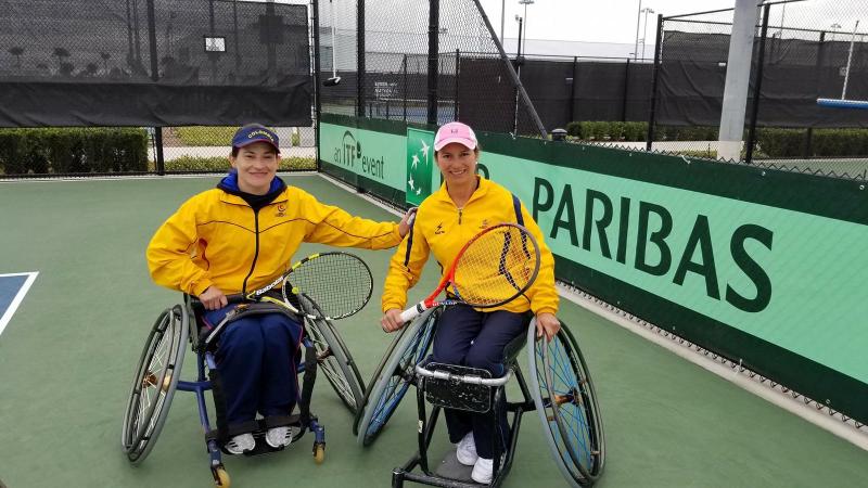 Johanna Sosa and Johana Martinez smiling and holding their rackets while wearing Colombia's official uniforms