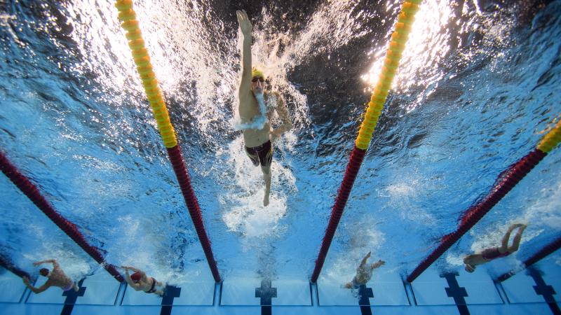 Man swimming in a pool seeing from under the pool