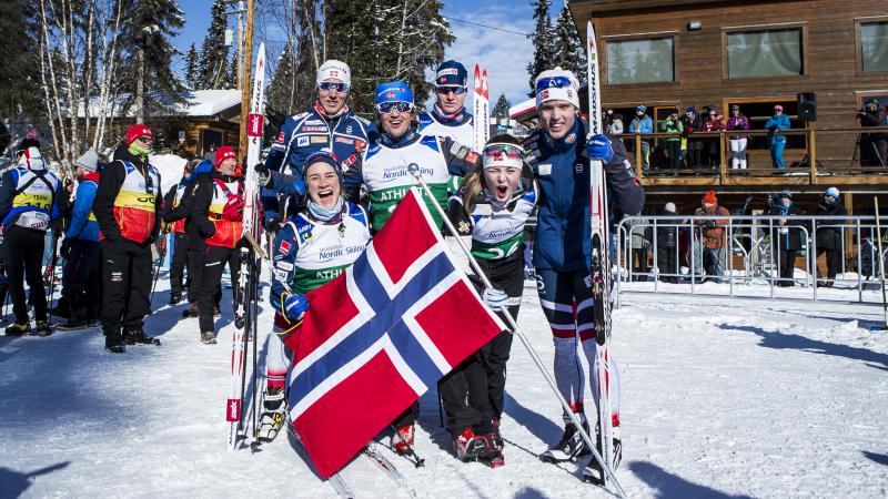 Group of Norwegian cross-country skiers happy posing together after a win