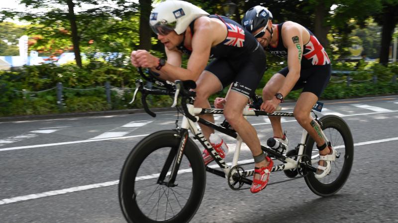 male Para triathlete Dave Ellis cycling on a tandem bike behind his guide