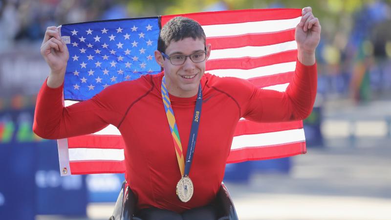 male wheelchair racer Daniel Romanchuk holding up a USA flag