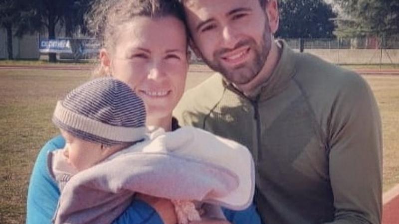 Female Para athlete Arjola Dedaj standing next to her male partner holding a baby boy