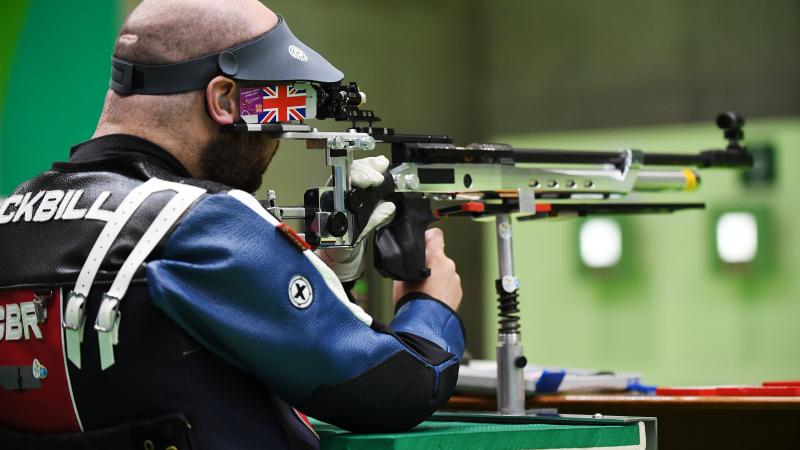 male Para shooter Ryan Cockbill prepares to shoot a rifle