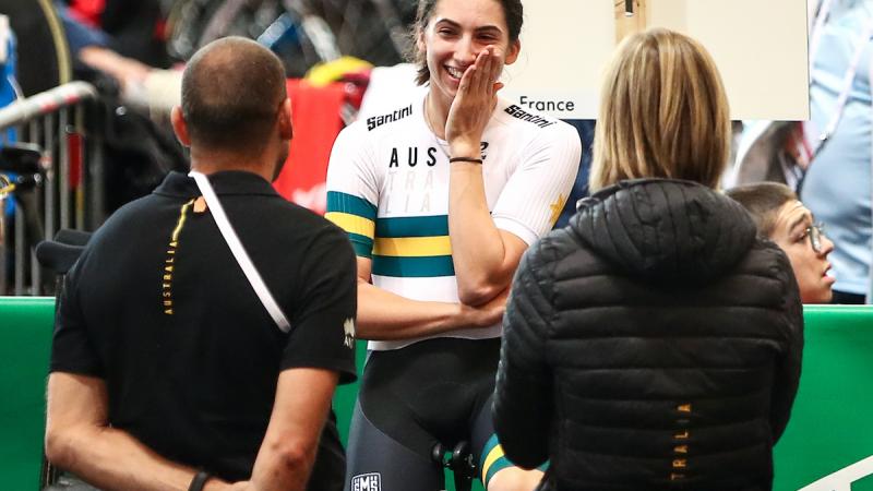 female Para cyclist Paige Greco smiles at two team officials