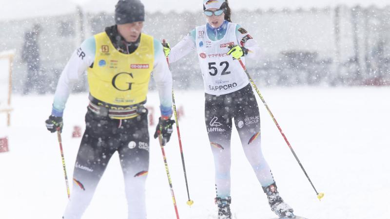 female Para Nordic skier Clara Klug skis towards the finish line behind her guide