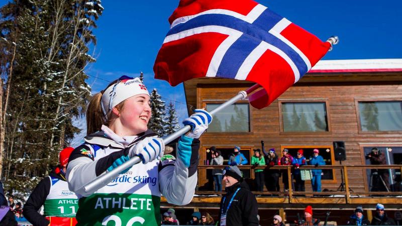 female Para Nordic skier Vilde Nilsen holds up a Norwegian flag