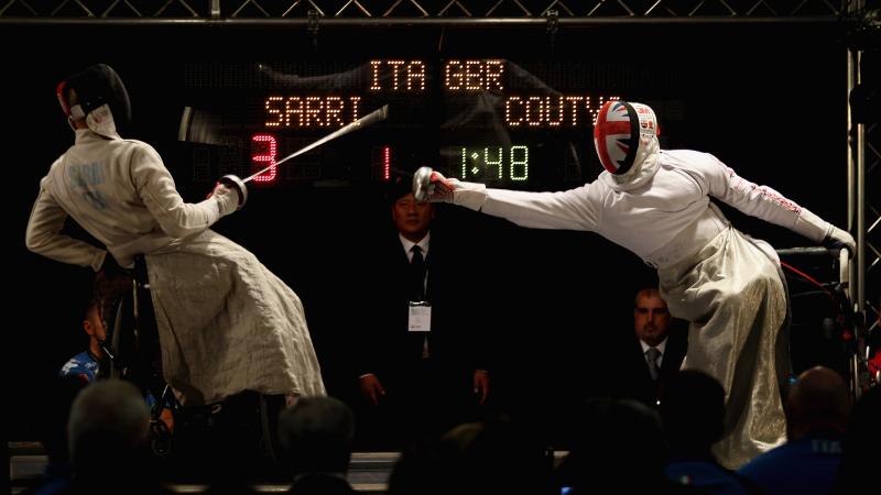 male wheelchair fencer Alessio Sarri leans back to avoid another fencer's foil