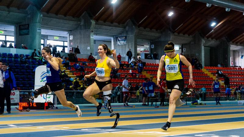 three female single amputee sprinters crossing the finish line