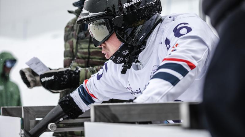 A snowboarder without the right arm on the starting gate