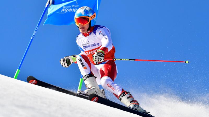 male Para alpine standing skier Theo Gmur skies through a gate