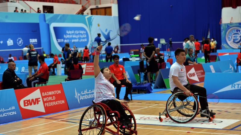 male and female Chinese Para badminton players in wheelchairs playing on the court