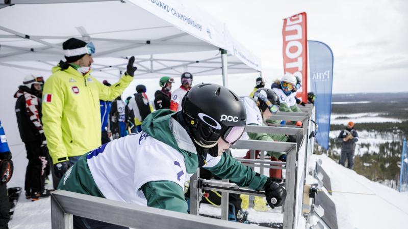Female snowboarders line up at the start gate ready to go