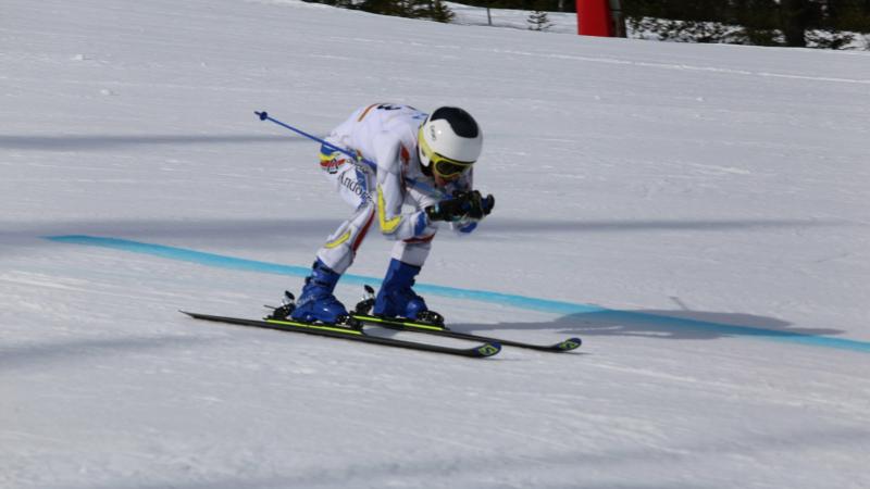 male Para alpine standing skier Roger Puig Davi crouches down as he crosses the finish line