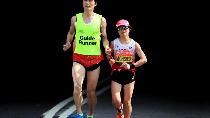 female vision impaired runner Misato Michishita running on the street with a male guide