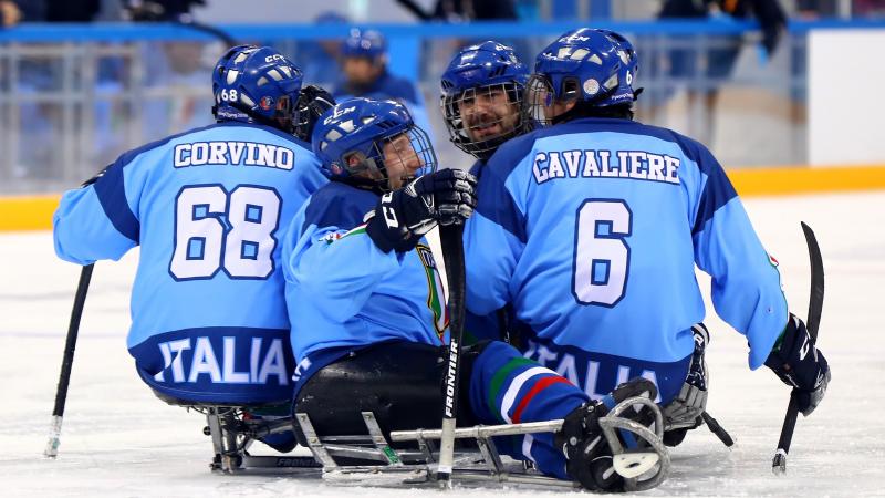 male Para ice hockey player Nils Larchi being hugged on the ice by his teammates