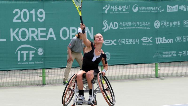 female wheelchair tennis player Marjolein Buis hits an overhead forehand on a hard court