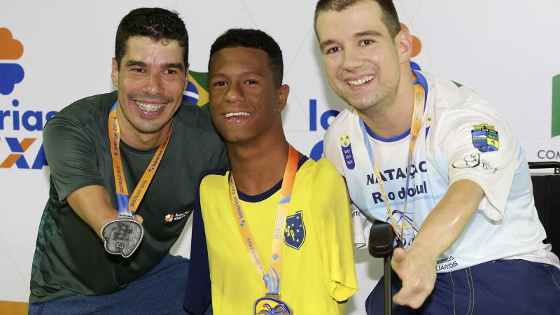 three male Para swimmers with their medals on the podium