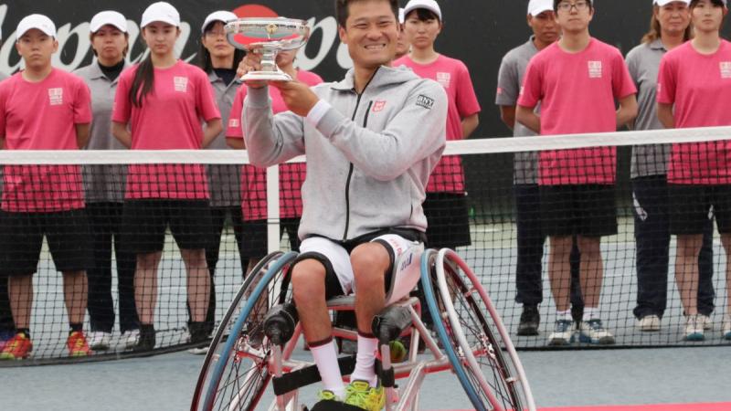 male wheelchair tennis player Shingo Kunieda smiling and holding up a silver trophy