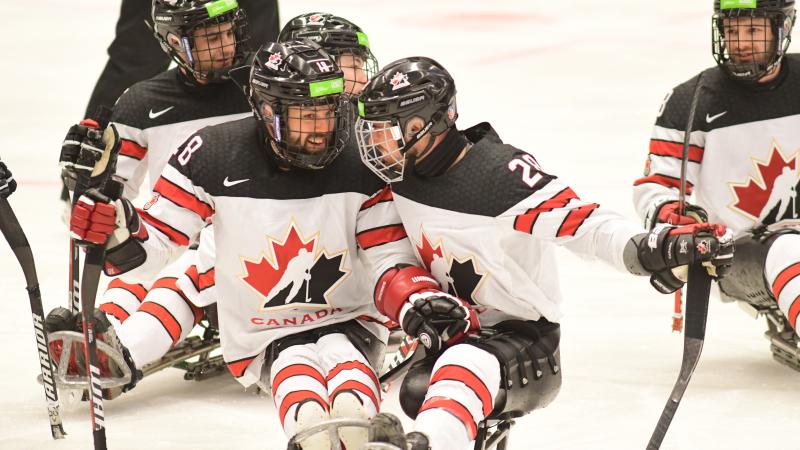 male Para ice hockey player Antoine Lehoux celebrates with another player hugging on the ice