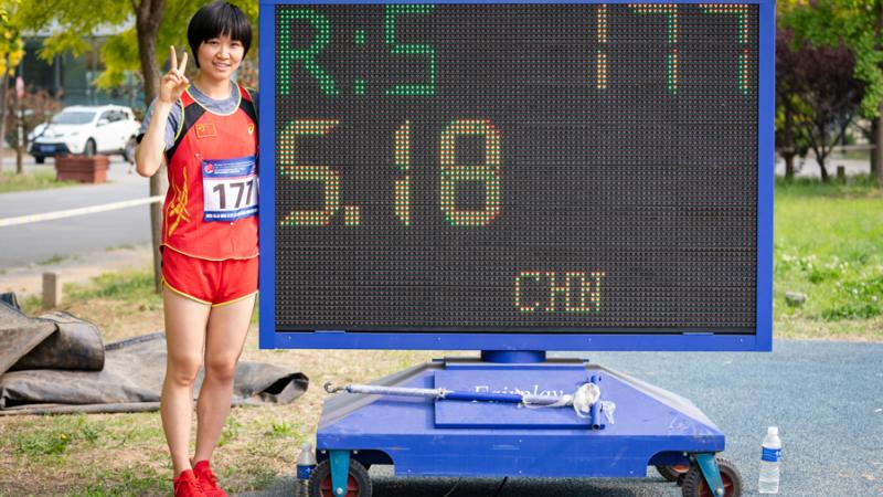 Chinese woman stands next to digital board displaying her world record