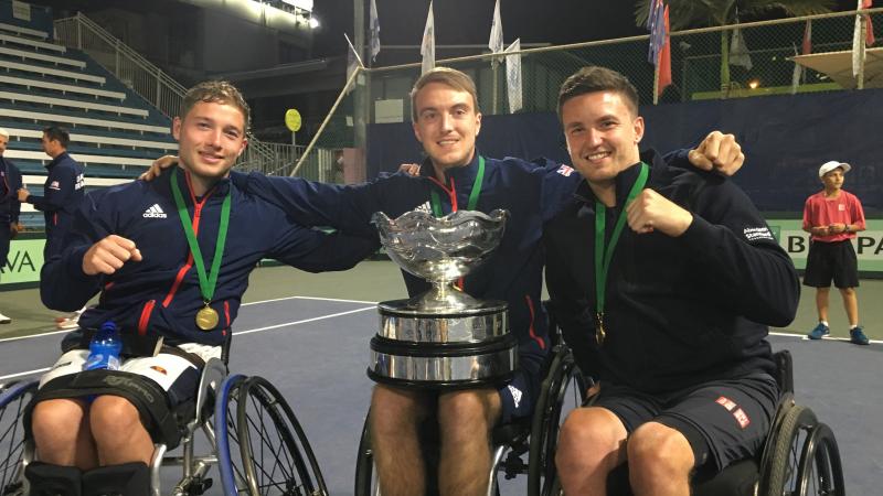 British players smile at the camera while showcasing the trophy