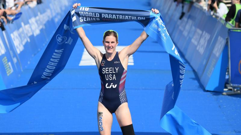 Female triathlete with left leg amputation celebrates as she crosses the finish line