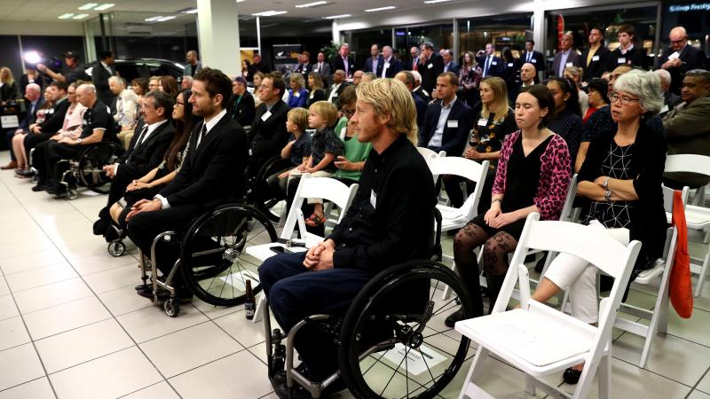 People gathered inside a room looking to the front and listening to a speaker