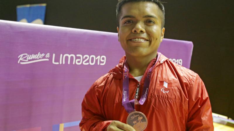 Diego Quispe smiles while he holds the bronze medal he won at the Lima World Cup