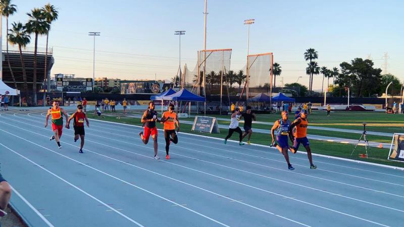 Four male vision impaired runners and thir guides racing on a track