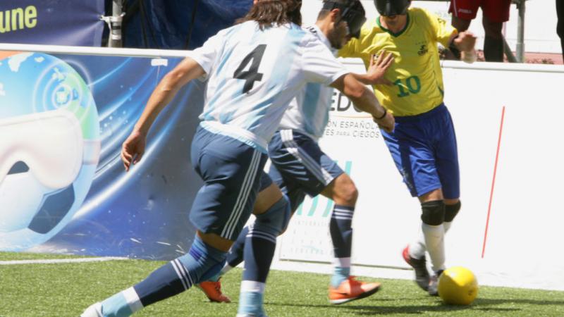 Ricardinho takes the ball while facing two Argentinian defenders