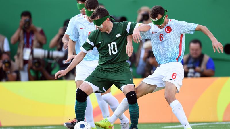 Brazilian blind football player Ricardinho controls the ball while two Turkish defenders try to take it from him