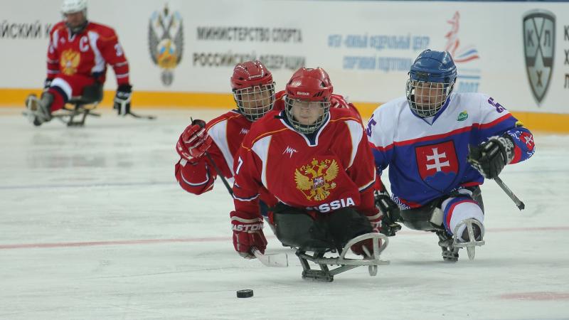 Two Russia Para ice hockey players and one Slovakian race for the puck