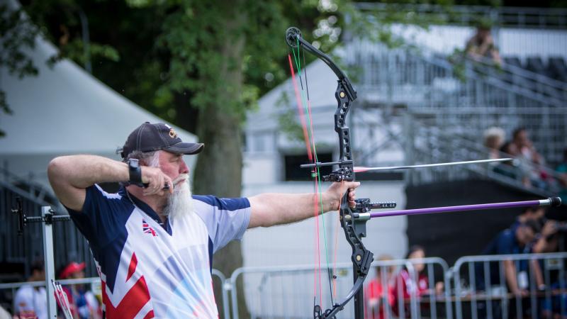 Man with long white beard shoots his bow and arrow