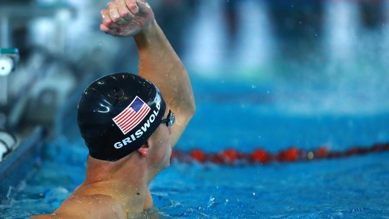 male Para swimmer Robert Griswold punches the air in the pool after winning a race