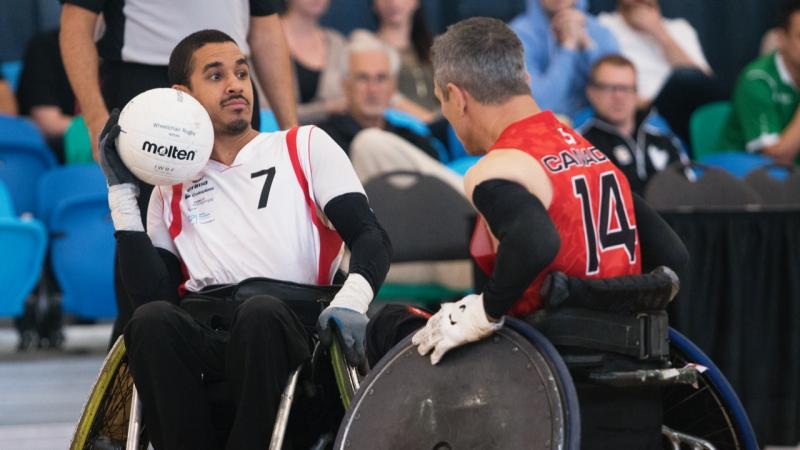 Swiss man in wheelchair rugby protects the ball against his opponent