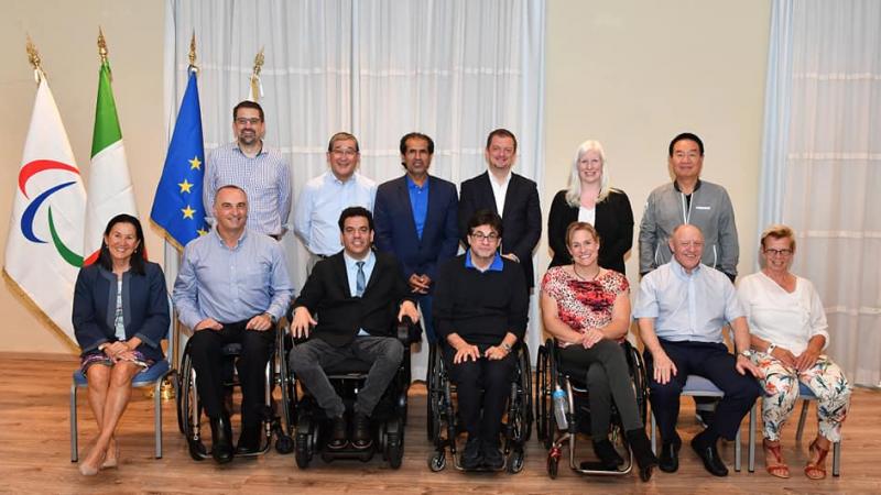 A group of six men and women standing behind a group of seven men and women